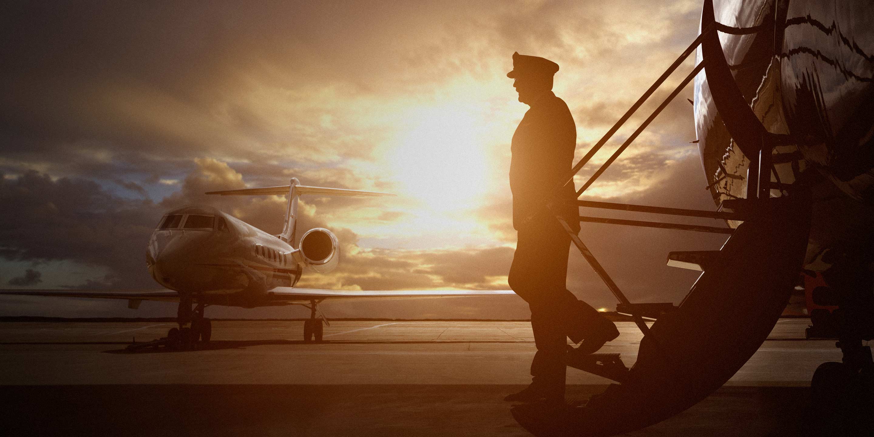 Pilot disembarking as second plane sits in the distance.
